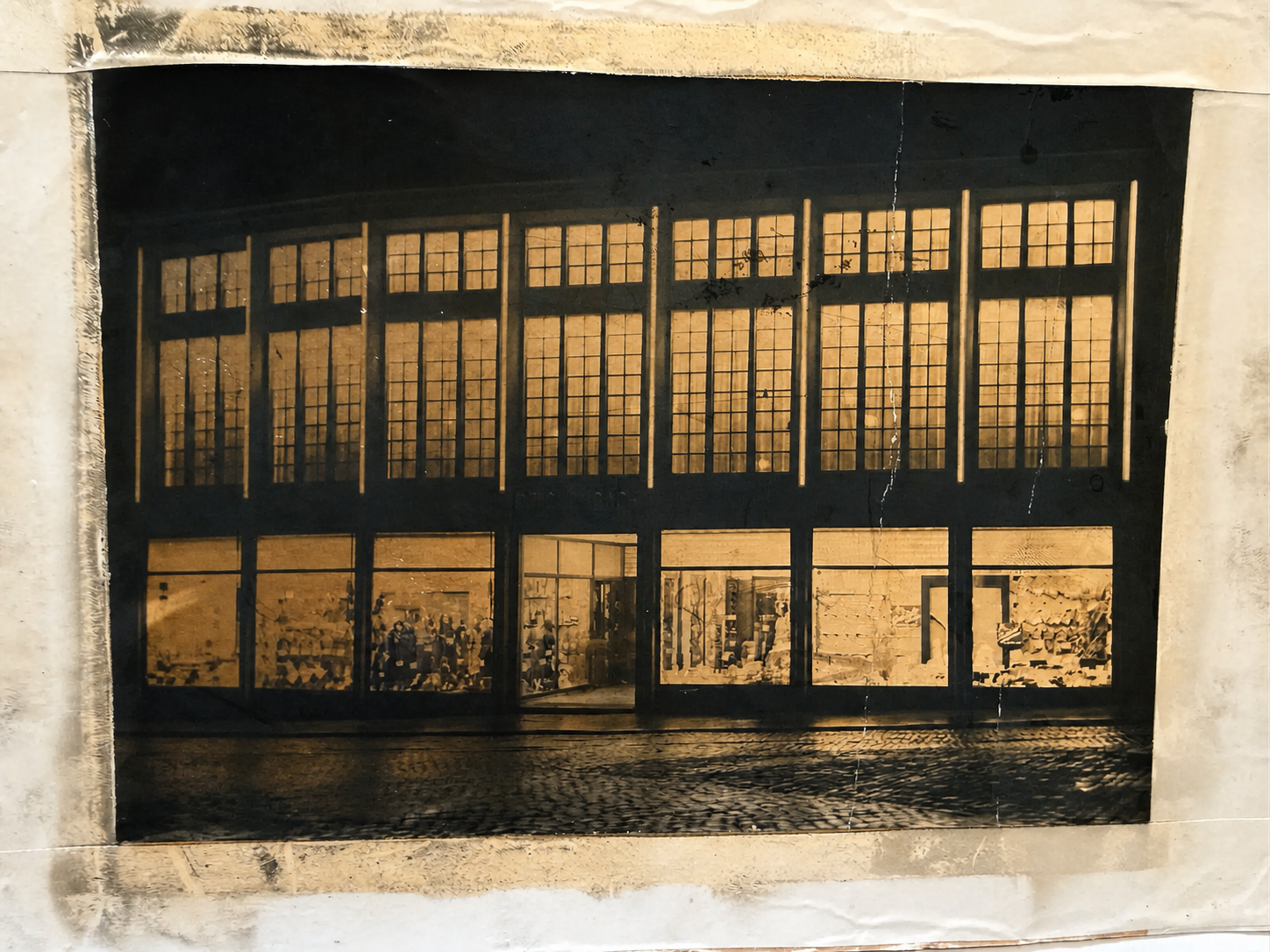 AI-generated interpretive reconstruction of the historic nighttime Kaufhaus Reichenbach façade photograph, retaining its illuminated windows and cobbled street