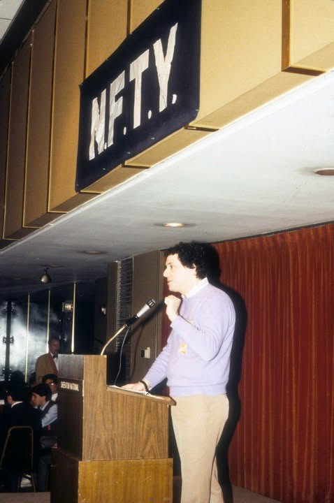 A young Paul J. Reichenbach speaking at a podium beneath a large NFTY sign