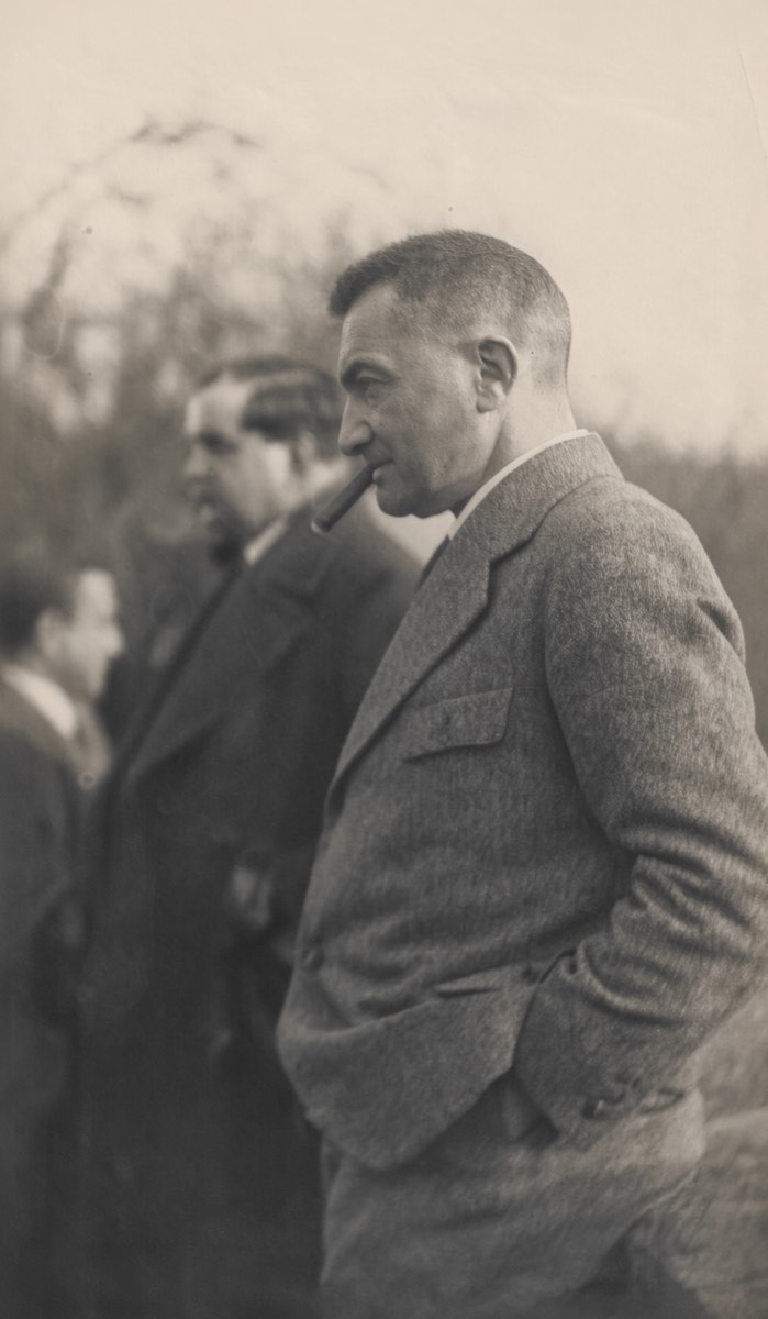 Color-enhanced presentation image of Paul Reichenbach standing in profile with a cigar at a gathering in Halberstadt