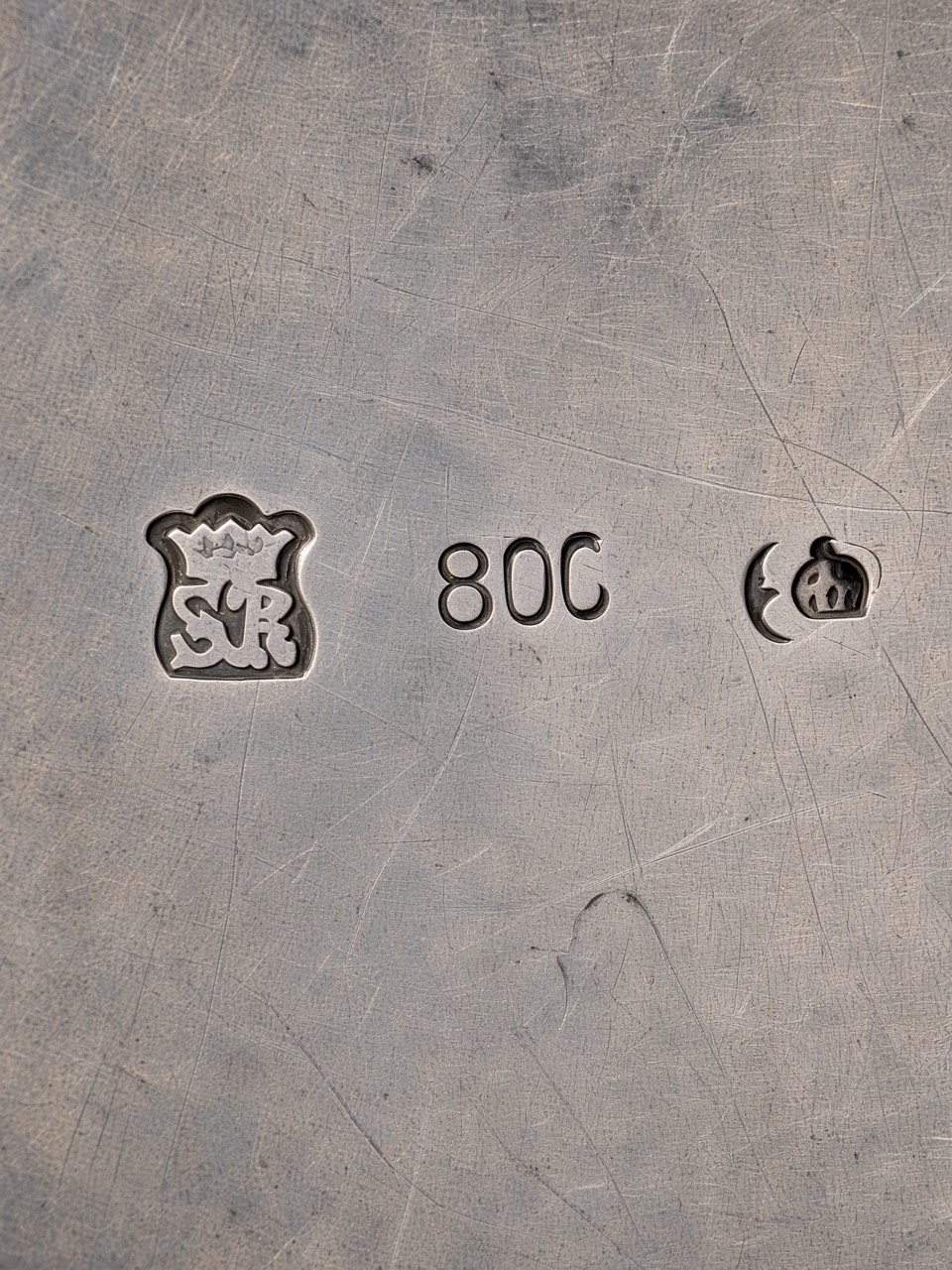 Close view of three struck marks on the scratched underside of the family silver-coloured box