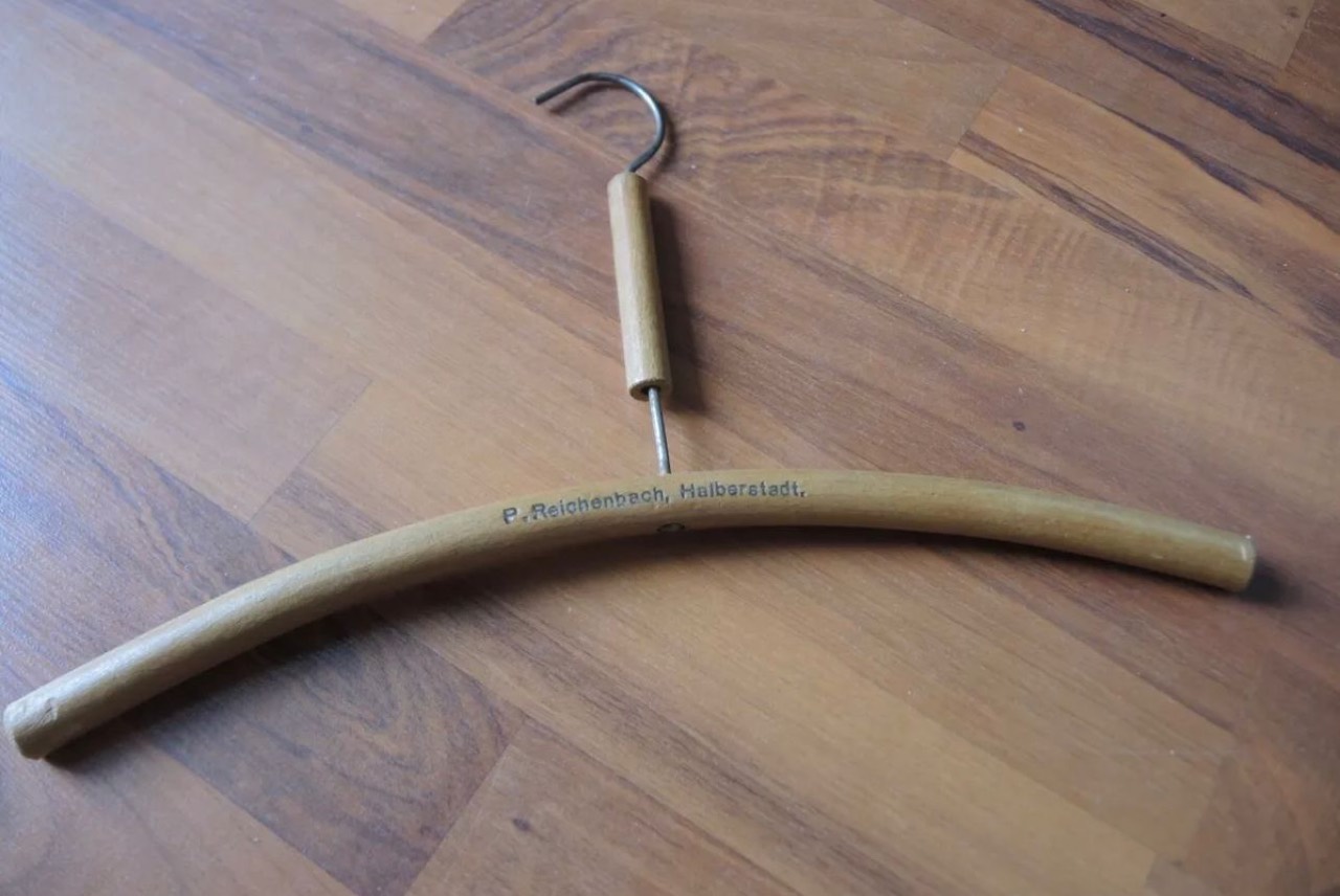 Curved wooden clothes hanger with a metal hook and the printed mark P. Reichenbach, Halberstadt